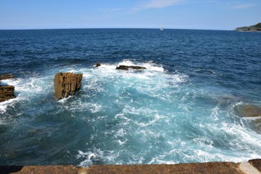 Dalgalar kayalar güneşli bir günde isabet