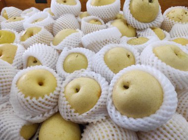 Süpermarkette tezgahın üstünde bir sepetin içinde armut.