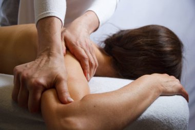 Kaplıcada yağı olan bir kıza ön kol masajı yapan bir masözün elleri, rahatlama konsepti, vücut bakımı konsepti.