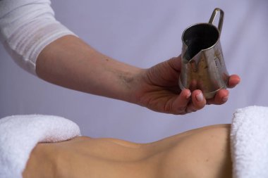 Bir kaplıca masözü müşterisini Ayurvedic masajına hazırlar. Vücuduna bir sürahi yağ dökerek.