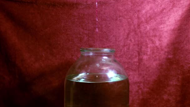 ムネシンを濾過し ガラス瓶に収集する段階 自宅でムーンシャインを作る 蒸留プロセス 赤い背景に — ストック動画