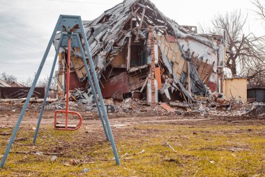 Ukrayna savaşı, Ukrayna 'daki bombardımandan sonra harap olmuş iki katlı bir yerleşim yeri, ön planda bir çocuk salıncağı var.