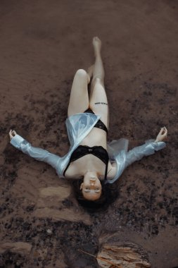 Siyah iç çamaşırlı bir kız ve temiz havada nehirde ıslak beyaz bir gömlek.