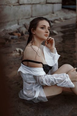 Siyah iç çamaşırlı bir kız ve temiz havada nehirde ıslak beyaz bir gömlek.