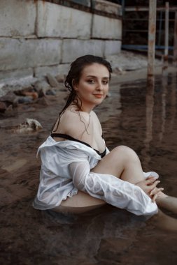 Siyah iç çamaşırlı bir kız ve temiz havada nehirde ıslak beyaz bir gömlek.