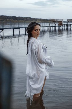 Siyah iç çamaşırlı bir kız ve temiz havada nehirde ıslak beyaz bir gömlek.