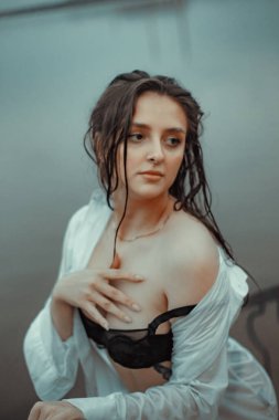 Siyah iç çamaşırlı bir kız ve temiz havada nehirde ıslak beyaz bir gömlek.