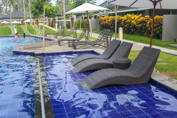 在一座异国情调的别墅里 用藤条做的用来放松的座位和游泳池边的日光浴 — 图库照片