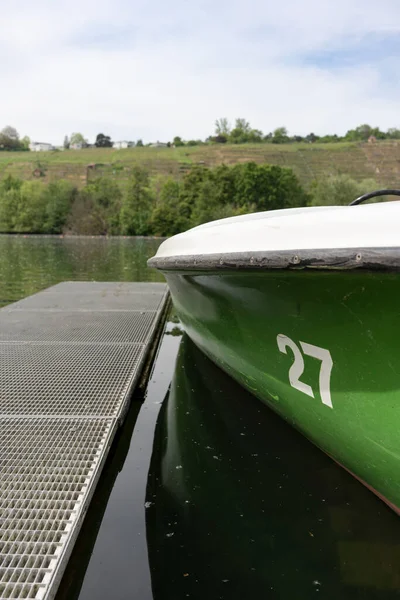 Limandaki bir rıhtıma demirlenmiş yeşil bir tekne. Göl. Ulaşım. Yaz tatilleri, eğlence konuları
