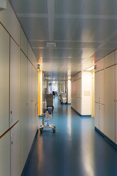 Mobile health diagnostic instrument unit at corridor of hospital ward. Doctors and nurses walking in hospital hallway, blurred motion.