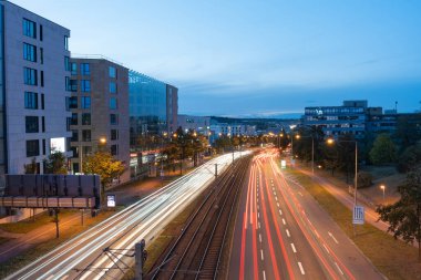 Şehirdeki gece trafiği, hareket halindeki araba ışıkları bulanık. Yoğun bir otoyolda gün batımında araba ışığı izleri var..