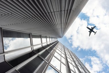 Gökyüzünde bir uçak uçuyor. Uçak bir gökdelenin üzerinden uçuyor..