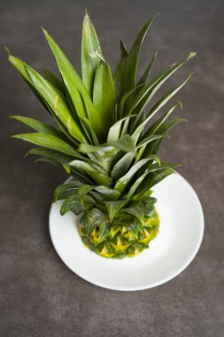 Masaya yakın plan ananas. Ananas yaprakları ve meyve tabakta kalır..