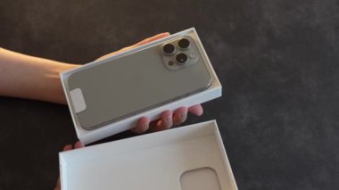 Satın alındıktan sonra paketlenmemiş yeni bir iPhone. Kız kutudan yeni bir iPhone 15 çıkardı..