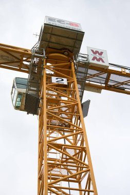 İnşaat alanında Sarı Kule Turnası. Gökyüzüne karşı inşa edilmiş uzun sarı bir vinç modern şehir gelişiminin ve mühendislik gücünün sembolü..