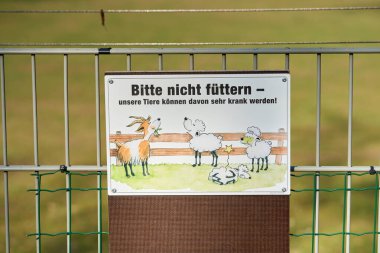 Stuttgart, Almanya 20 Mayıs 2025. Hayvanat bahçesinde bir uyarı işareti. Tabelada, evcil hayvan çiftliğine gelen ziyaretçilerin hayvanları ev yemeğiyle beslememesi gerektiği yazıyor..