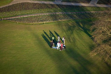 Stuttgart, Almanya 23 Mai 2025. Mutlu dostların çimenlerde birlikte dinlenmesi görüşünün üstünde. Bir grup insan çimenlikteki parkta eğleniyor. Yukarıdan görüntüle.