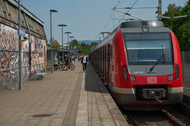 Stuttgart, Almanya 3 Ağustos 2025. Almanya 'daki şehir istasyonunda modern kırmızı bölge treni. Alman DB treni, güneşli bir günde insanların platformda yürüdüğü grafiti kaplı istasyonda durdu..