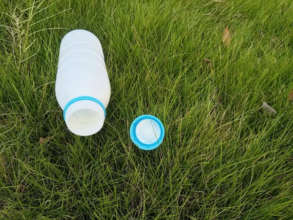 White Bottle And Cap Gracefully Resting On Lush Green Grass