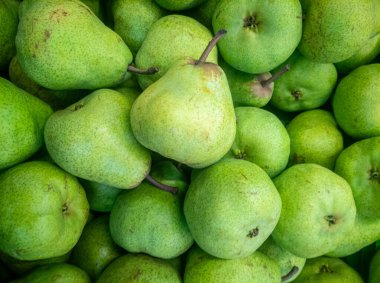Bir araya toplanmış taze yeşil armutlar grubu canlı renklerini ve doğallıklarını sergiliyorlar. Markette ya da markette satışa hazır.