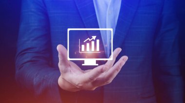 İş adamı grafikte iş büyümesini gösteriyor. Eller grafiklere dokunuyor. Sanal arayüz teknolojisi ve finansal sembollerle artan karı temsil ediyor.