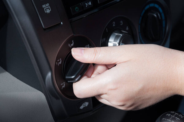 Woman hand turning on car air conditioning system