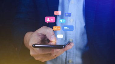 Bildirimler, mesajlar, akıllı telefon ekranındaki yorumlar gibi simgelerle cep telefonlarında sosyal medya ve dijital çevrimiçi pazarlama kavramları kullanan insanlar.