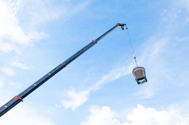 İnşaat alanında mavi gökyüzü arkaplanlı tel üzerinde asılı çimento ya da beton kova