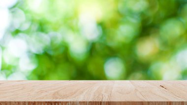 Arkaplanda bulanık yeşil bokeh bulunan boş kahverengi ahşap masa, tanıtım ve reklam ürünlerini tanıtmak için