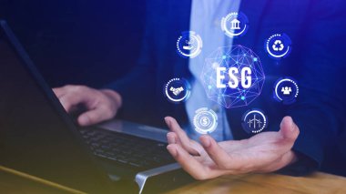 Ağ bağlantısında sürdürülebilir ve etik sektörde çevre, sosyal ve yönetim için elinde ESG simgesi konsepti, ekrandaki işadamı düğmesine basıyor.