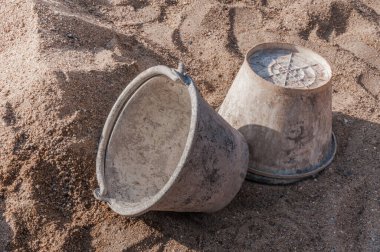 İnşaat alanındaki kumun üzerine çimento dökülmüş plastik kova.