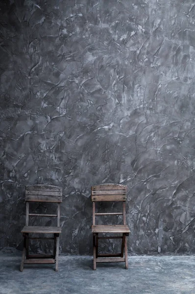 深色混凝土墙质感的老式木椅 图库照片