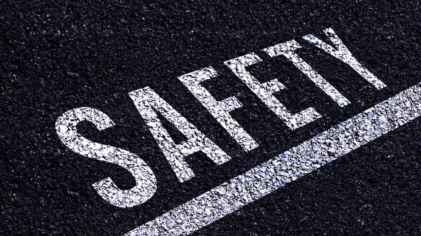 Safety first text written on the road in middle of the asphalt road, Safety first word on street.