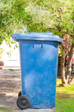 Kirli mavi çöp tenekesi Parkta tekerleği olan