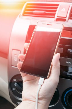 Arabada akıllı telefon, arabada şarj fişi, araba kullanırken telefona basan insanlar.