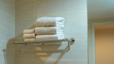 Banyodaki paslanmaz rafta havlu. Kaplıca ve hijyen için katlanmış temiz tekstil ve modern otel odası.