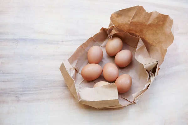 Коричневое Яйцо Бумажном Пакете Позади Свежие Куриные Яйца Деревянном Столе — стоковое фото