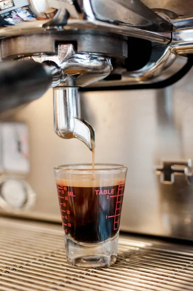 closeup black coffee in measuring cup put on coffee maker,coffee machine making espresso