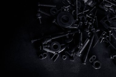 Kullanılmış Metalik düğümün soyutluğu fındıkları ve çivi cıvatalarını koyu arkaplandaki vidalıyor