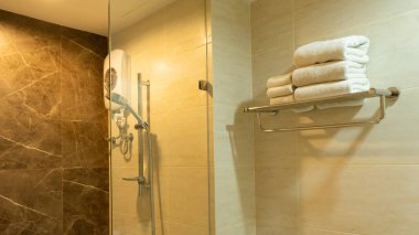 Banyodaki paslanmaz rafta havlu. Kaplıca ve hijyen için katlanmış temiz tekstil ve modern otel odası.
