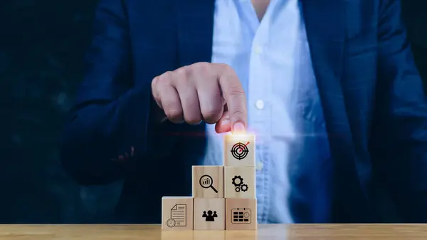 Concept of business planning strategy, hand choose the wooden cube block with icon aiming goal icon Action plan,success and business target concept,company strategy development.