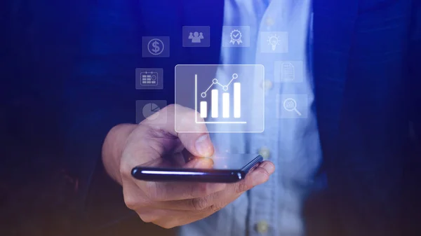 Data analytics and business intelligence BI concept with chart and graph icons on digital screen interface on smartphone and business people in the background.