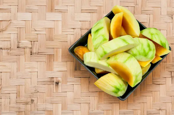 成熟的芒果 可以在竹编的背景上用黑盘子吃 — 图库照片