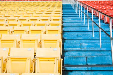 Stadyumdaki boş turuncu ve sarı koltuklar, futbol stadyumundaki sıralar.