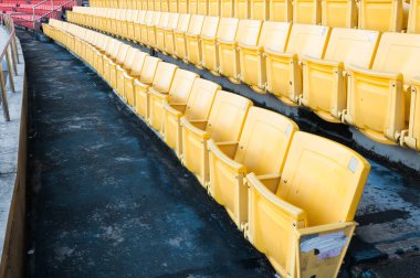 Stadyumdaki boş sarı koltuklar, futbol stadyumundaki sıralı yürüyüş yolları.