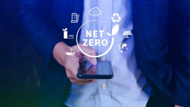 Ağ Sıfır ve Karbon Nötr Kavramları, Ağ Sıfır sera gazı emisyon hedefi, İklim Nötr uzun stratejisi, NetZero simgesini akıllı telefon ile elinde tutan İşadamı.