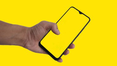 Çevrimiçi satış ürünleri reklamları için sarı arka planda bir cep telefonu tutuyorlar.