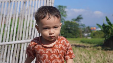 Bebek mutlu görünüyor ve temiz ve ferahlatıcı sabah havasının tadını çıkarıyor, neşe ve sıcaklık dolu bir atmosfer yaratıyor.