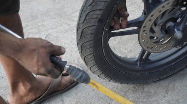 Adam lastikle araba tamir ediyor.