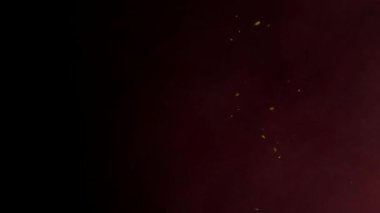 Soyut koyu renk eğimli arka plan, sıcak bir his için rastgele süzülen sarı parıltılı kırmızı ve turuncu bir renk içerir..